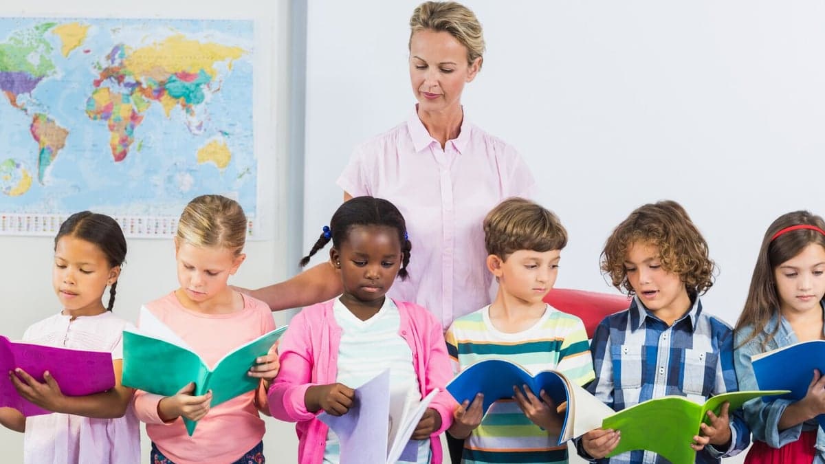 Teacher helping a group of children read books